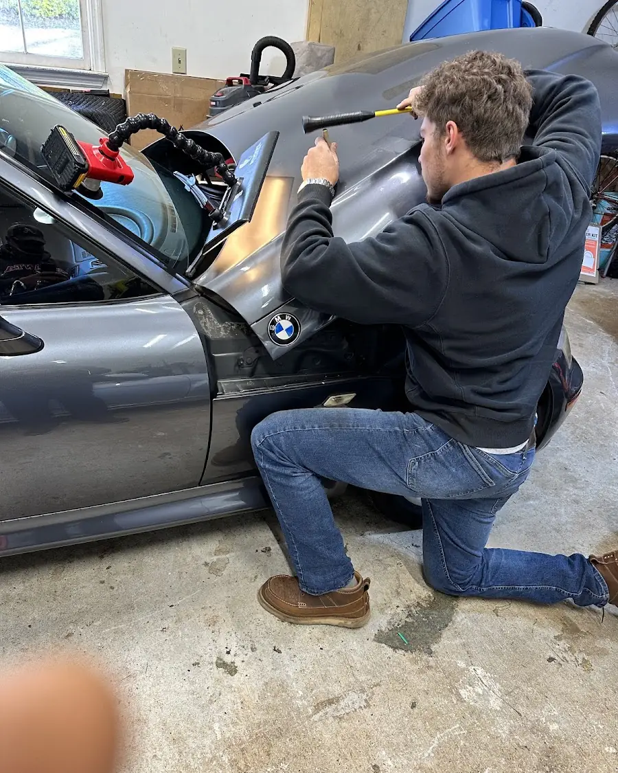 Camren working a dent out of a BMW's panel from behind the trim